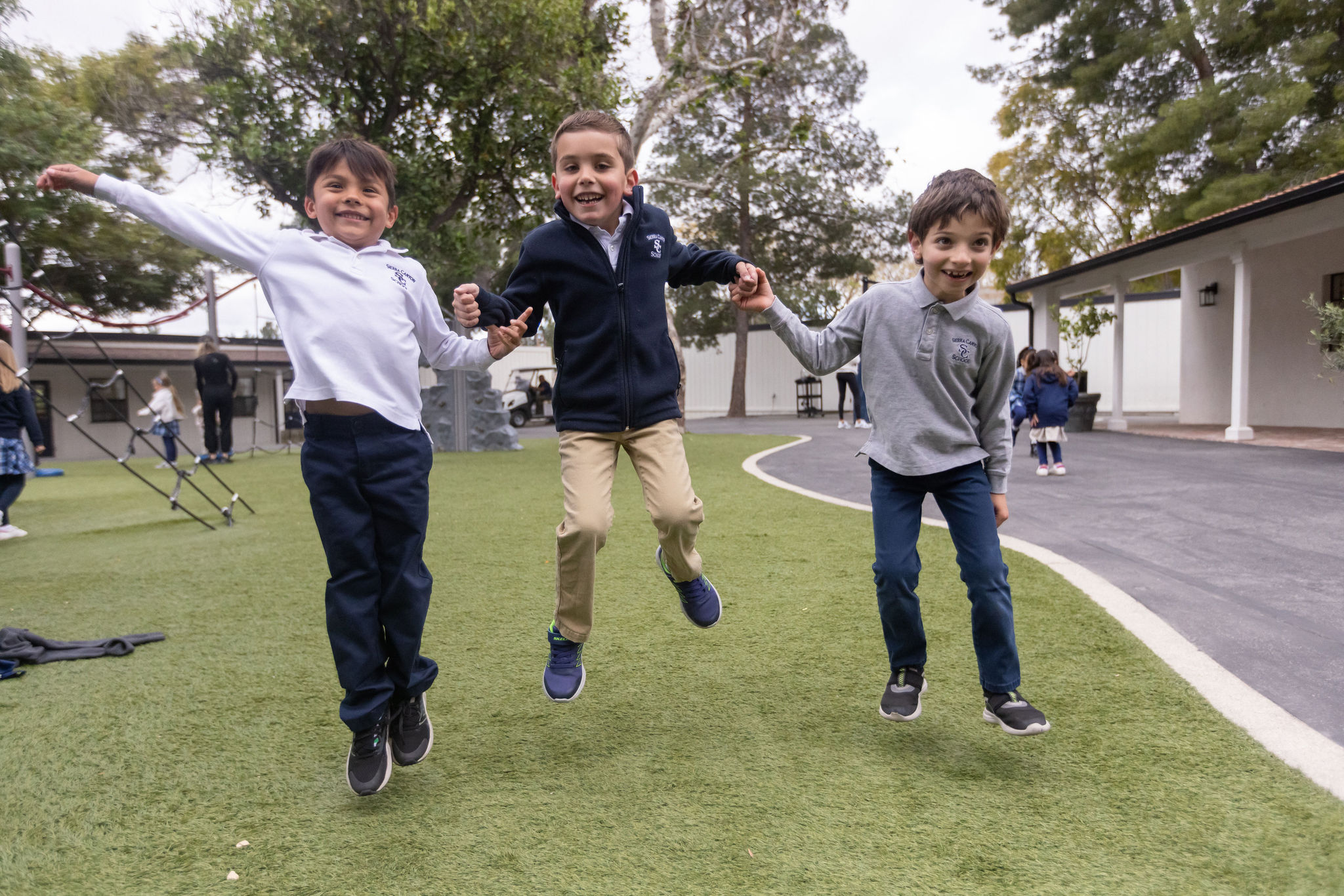 Three happy lower school students, jumping and laughing