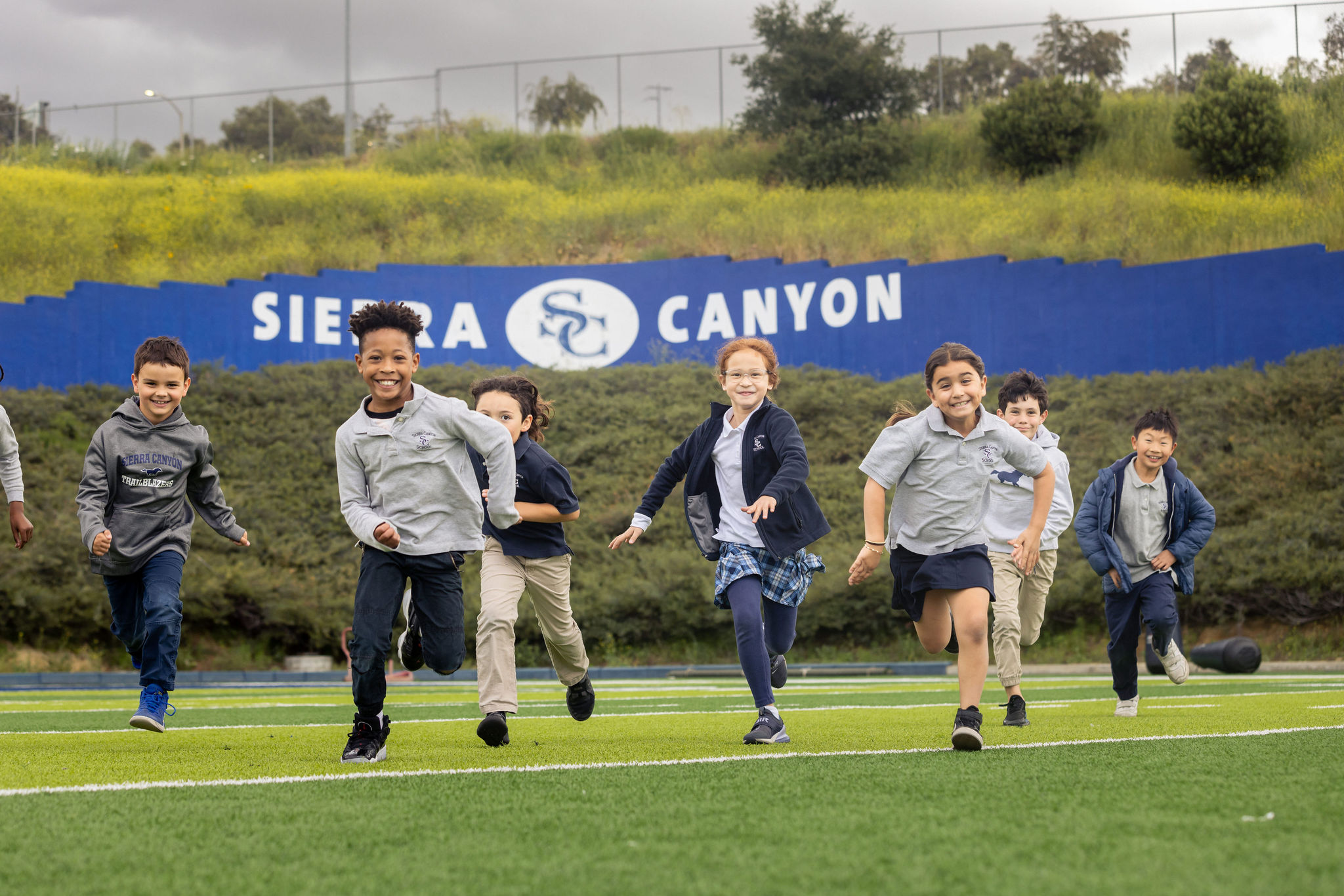 Smiling Sierra Canyon students, a boy and a girl, happily walking down a flight of stairs.
